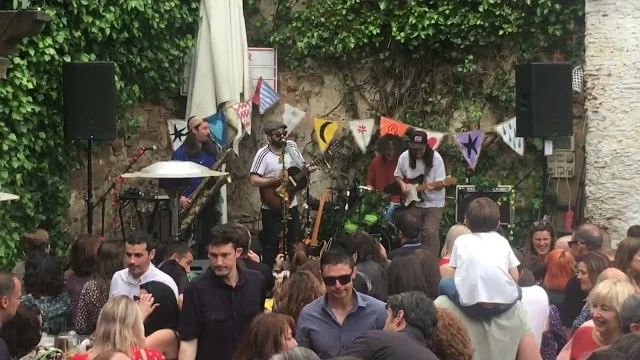 Grupo tocando en el escenario del patio de El Corral de las Cigüeñas con banderines y el público celebrando
