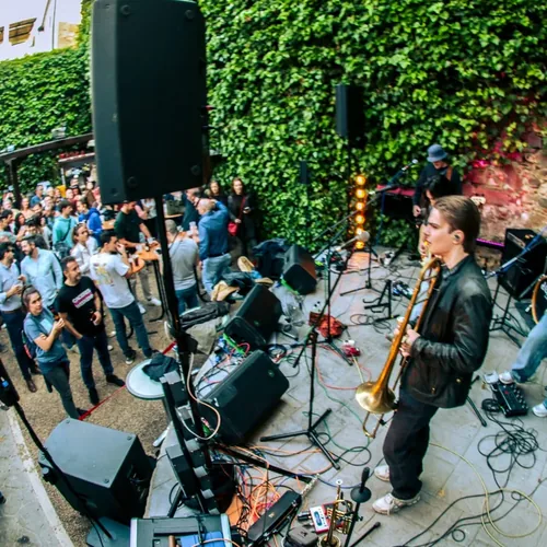 Concierto de día en el patio de El Corral de las Cigüeñas: una trompetista sobre el escenario y el público sentado alrededor