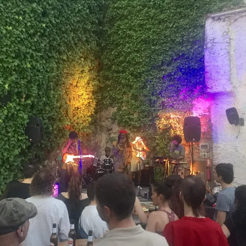 Concierto de noche en el patio de El Corral de las Cigüeñas, con el muro de hiedra iluminado de azul y morado