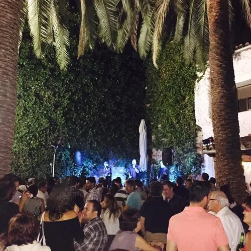 Público de noche bajo las palmeras del patio de El Corral de las Cigüeñas durante un concierto