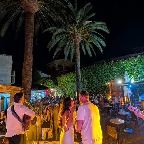 Ambiente nocturno en el patio de El Corral de las Cigüeñas, con las palmeras iluminadas y gente charlando