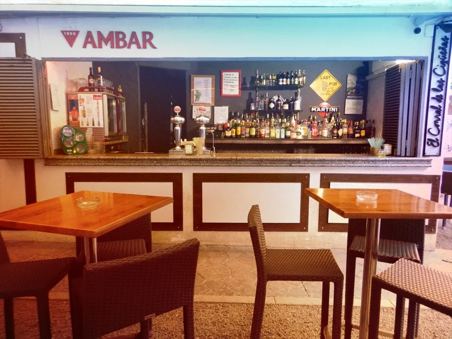 La barra principal de El Corral de las Cigüeñas, con el rótulo de Ambar, los tiradores de cerveza, la estantería de botellas y las mesas delante