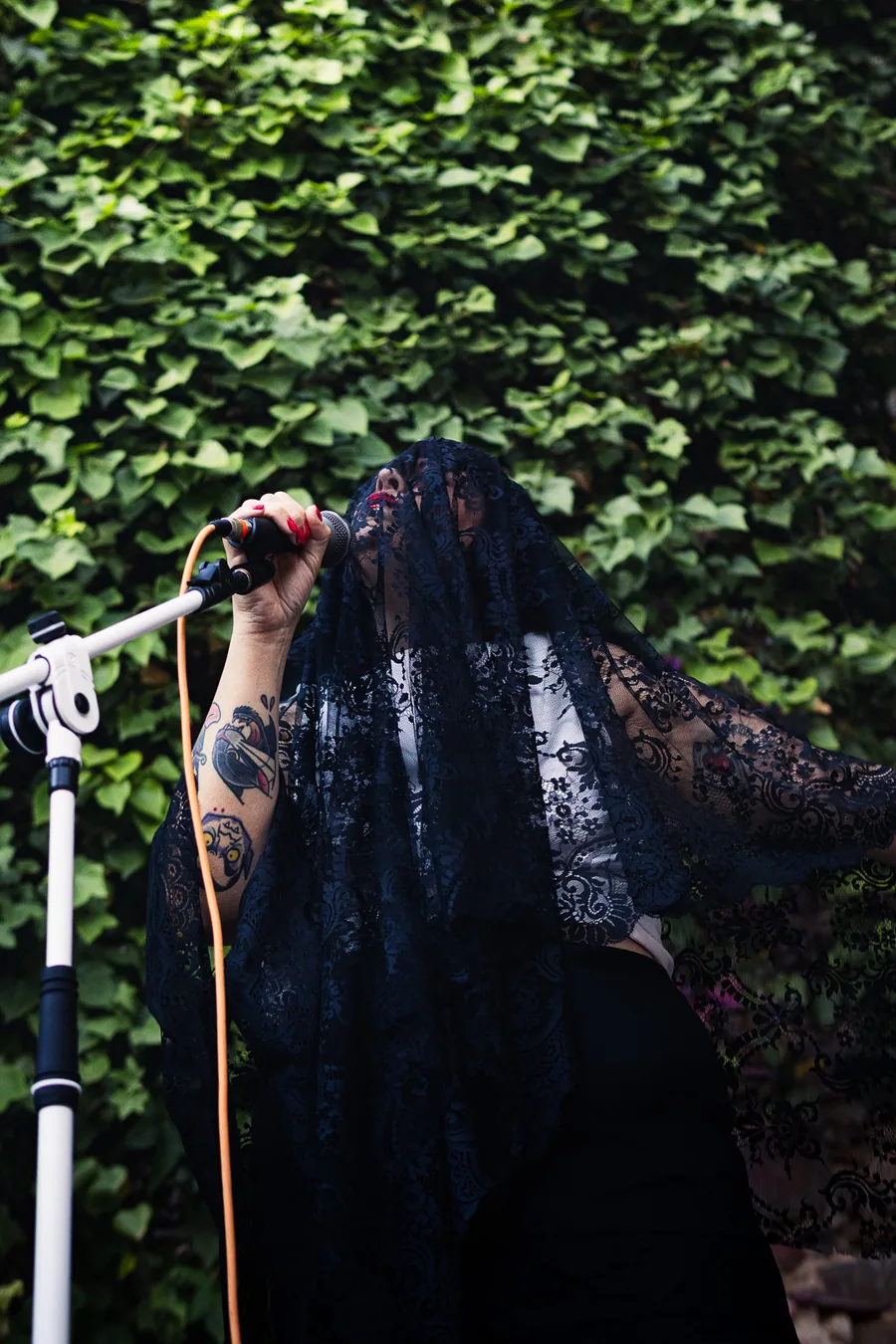 Cantante con mantilla de encaje negro actuando ante el muro de hiedra del patio de El Corral de las Cigüeñas