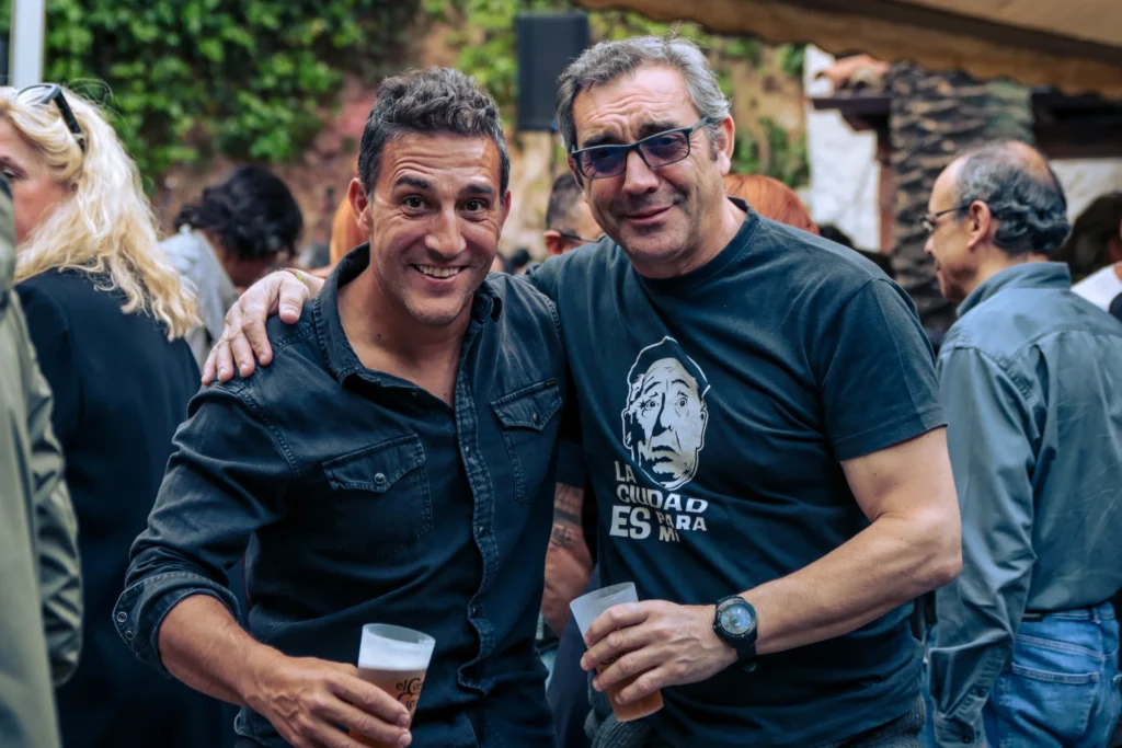 Dos amigos sonríen con la cerveza en la mano en el patio