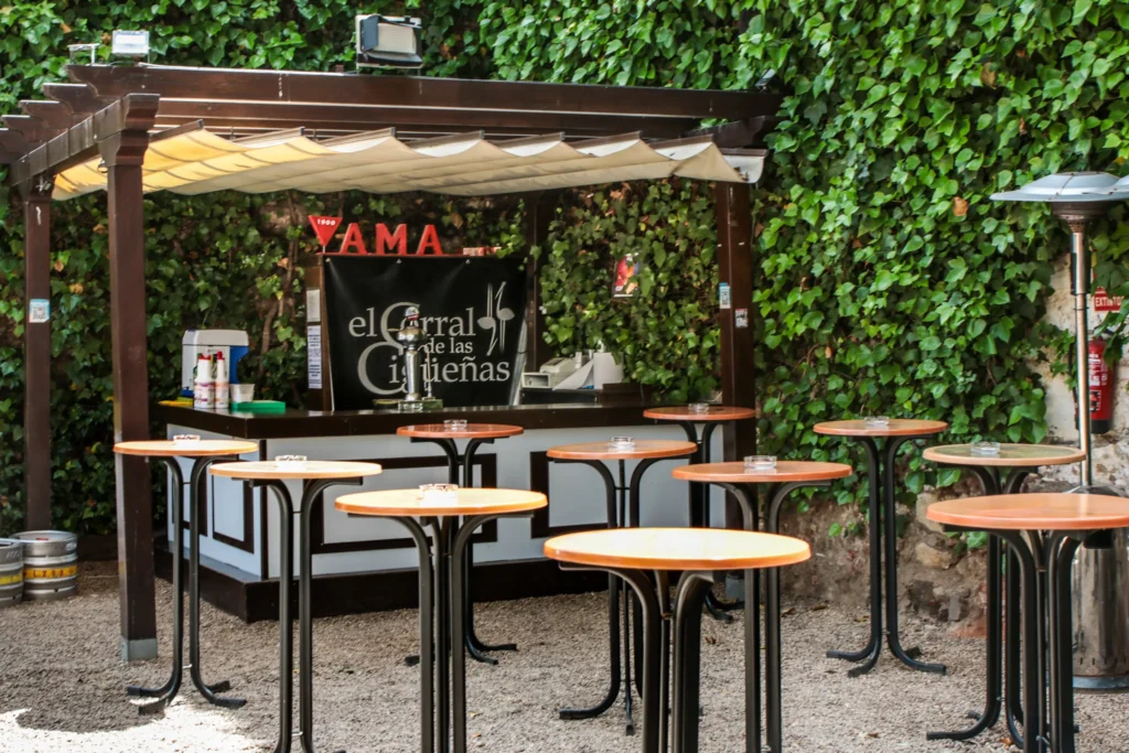 La pérgola de madera del patio con sus mesas y taburetes